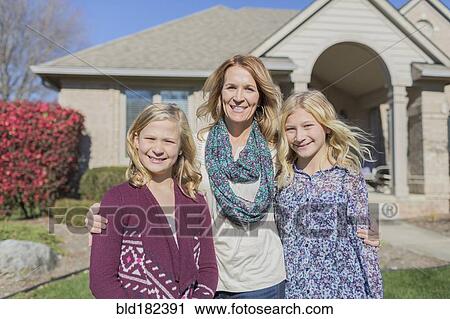 Stock Image - Caucasian mother and daughters smiling in yard. Fotosearch