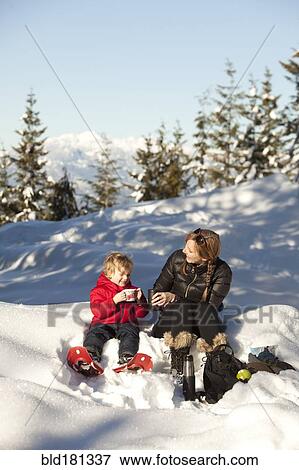 Stock Photo - Caucasian mother and son drinking hot cocoa in snow. Fotosearch