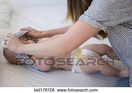 Stock Photograph - Caucasian mother changing baby diaper. Fotosearch