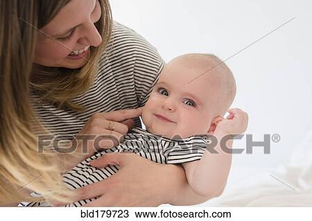 Caucasian mother holding baby daughter on bed View Large Photo Image Stock Image - Caucasian mother holding baby daughter on bed. Fotosearch