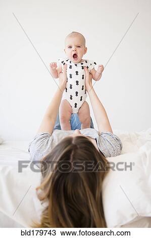 Caucasian mother holding baby daughter on bed View Large Photo Image Stock Image - Caucasian mother holding baby daughter on bed. Fotosearch