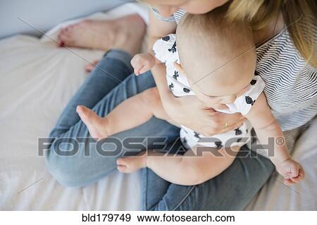Caucasian mother holding baby daughter on bed View Large Photo Image Stock Photo - Caucasian mother holding baby daughter on bed. Fotosearch