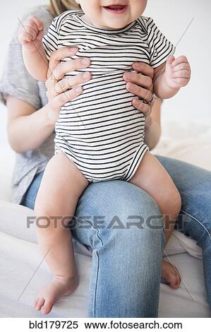Stock Photography - Caucasian mother holding baby daughter on bed. Fotosearch