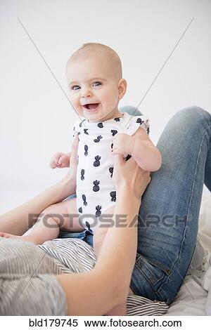 Caucasian mother holding baby daughter on bed View Large Photo Image Stock Photography - Caucasian mother holding baby daughter on bed. Fotosearch