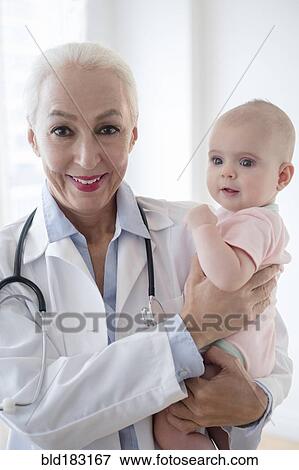 Caucasian pediatrician holding baby patient View Large Photo Image Stock Photo - Caucasian pediatrician holding baby patient. Fotosearch