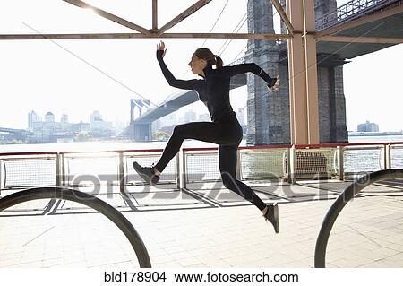 Picture - "Caucasian runner jumping on waterfront, New York, New York, United States". Fotosearch