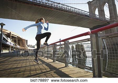 Stock Photo - "Caucasian runner stretching on waterfront, New York, New York, United States". Fotosearch