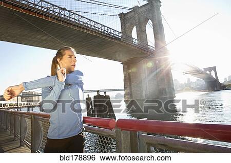 Stock Photograph - "Caucasian runner stretching on waterfront, New York, New York, United States". Fotosearch