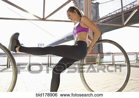 Stock Photograph - "Caucasian runner stretching on waterfront, New York, New York, United States". Fotosearch