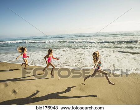 Stock Photo - Caucasian sisters running on beach. Fotosearch