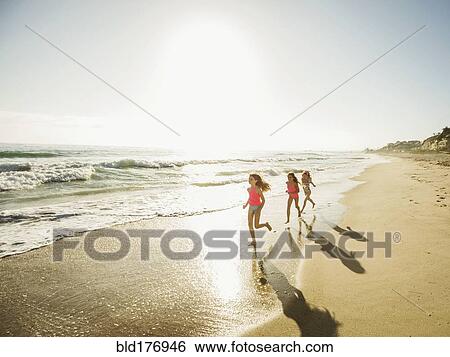 Stock Photograph - Caucasian sisters running on beach. Fotosearch