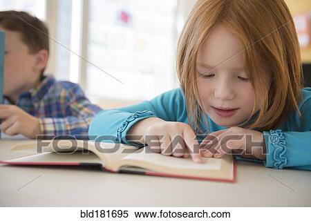 Stock Photography - Caucasian student reading in classroom. Fotosearch