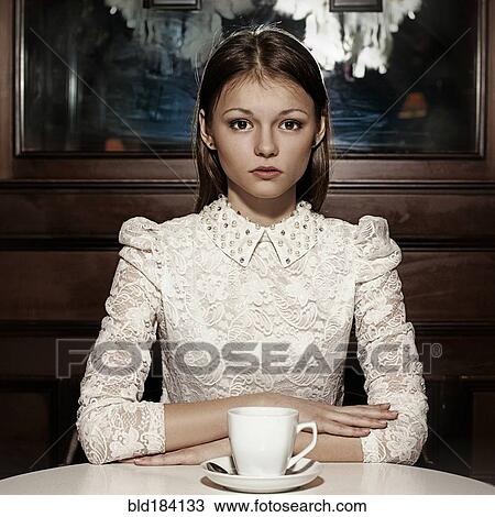 Stock Image - Caucasian teenage girl drinking coffee in restaurant. Fotosearch