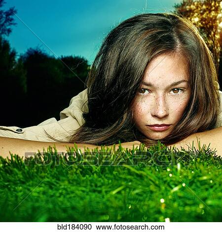 Stock Image - Caucasian teenage girl laying in grass. Fotosearch