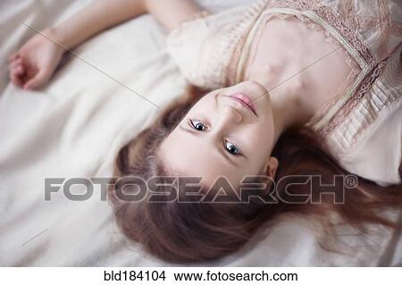Picture - Caucasian teenage girl laying on bed. Fotosearch