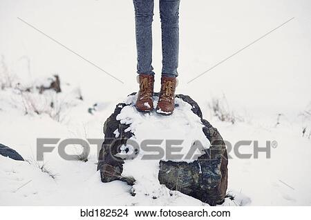 Picture - Caucasian teenage girl standing on snowy rock. Fotosearch