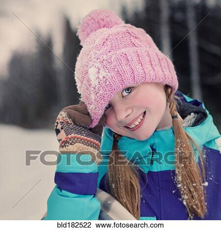 Stock Image - Caucasian teenage girl wearing beanie hat in snow. Fotosearch