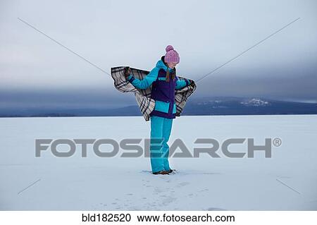 Stock Image - Caucasian teenage girl wrapped in blanket in snow. Fotosearch