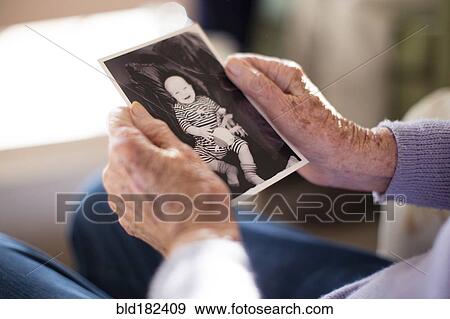 Stock Photo - Caucasian woman admiring photograph of baby. Fotosearch