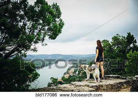 Stock Photograph - Caucasian woman and dog admiring scenic view. Fotosearch