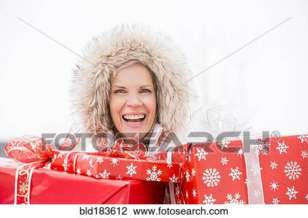 Stock Image - Caucasian woman carrying Christmas gifts. Fotosearch