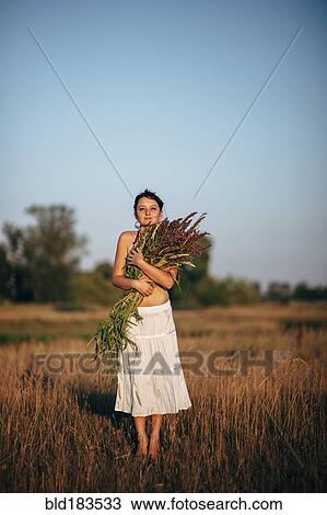 Caucasian woman carrying flowers in rural field View Large Photo Image Stock Image - Caucasian woman carrying flowers in rural field. Fotosearch