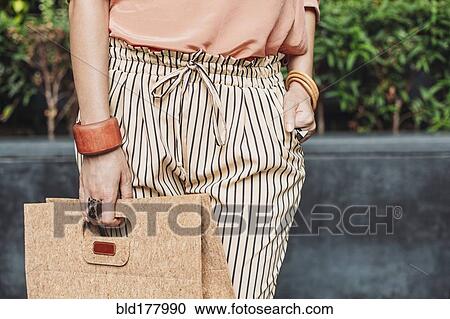 Stock Image - Caucasian woman carrying purse outdoors. Fotosearch