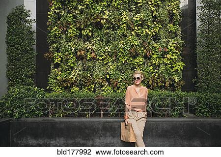 Stock Image - Caucasian woman carrying purse outdoors. Fotosearch