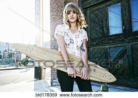 Caucasian woman carrying skateboard View Large Photo Image Stock Photo - Caucasian woman carrying skateboard. Fotosearch