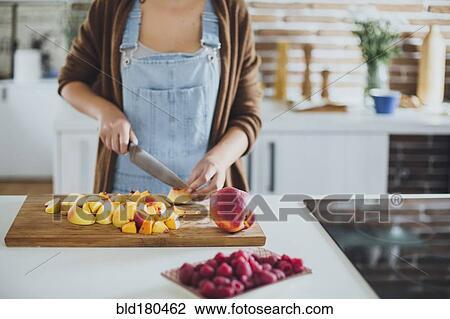 Stock Image - Caucasian woman chopping fruit in kitchen. Fotosearch
