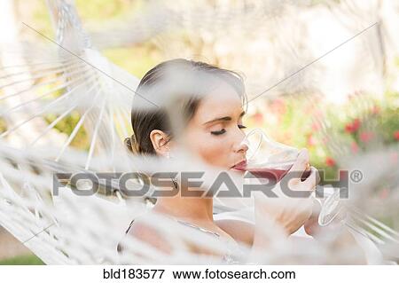 Caucasian woman drinking cocktail in hammock View Large Photo Image Stock Photo - Caucasian woman drinking cocktail in hammock. Fotosearch