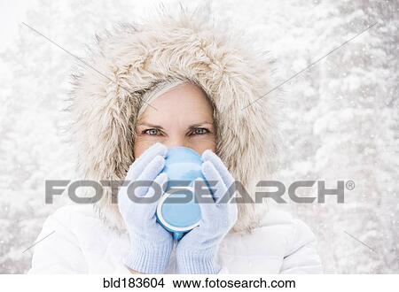 Picture - Caucasian woman drinking coffee in snow. Fotosearch