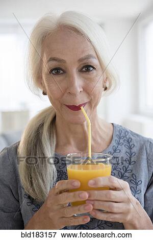 Stock Photo - Caucasian woman drinking juice through straw. Fotosearch