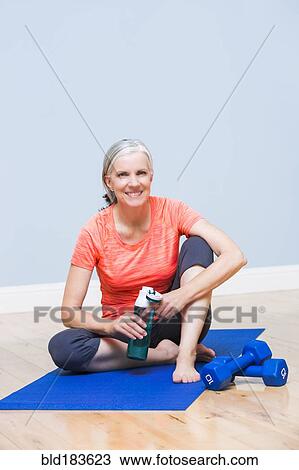 Caucasian woman drinking water on yoga mat View Large Photo Image Stock Image - Caucasian woman drinking water on yoga mat. Fotosearch