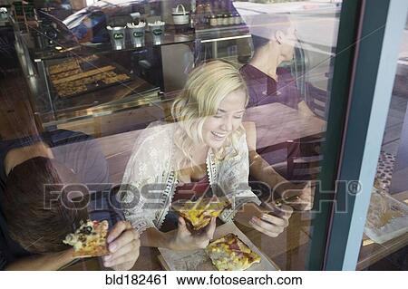 Stock Image - Caucasian woman eating pizza in cafe. Fotosearch