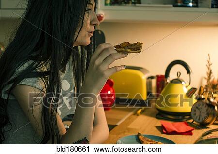 Caucasian woman eating pizza in kitchen View Large Photo Image Stock Image - Caucasian woman eating pizza in kitchen. Fotosearch