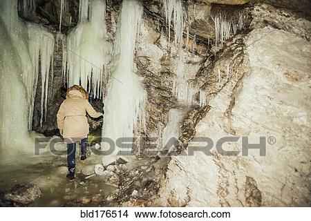 Picture - Caucasian woman exploring stalactites in cave. Fotosearch