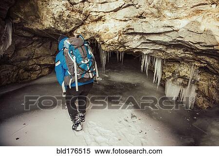 Stock Photography - Caucasian woman exploring stalactites in cave. Fotosearch