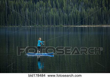 Caucasian woman fishing from paddle board in river View Large Photo Image Picture - Caucasian woman fishing from paddle board in river. Fotosearch