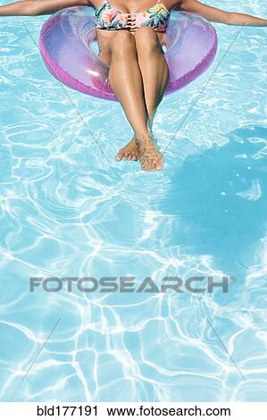 Stock Image - Caucasian woman floating in swimming pool. Fotosearch
