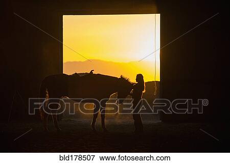 Stock Photo - Caucasian woman grooming horse in barn. Fotosearch