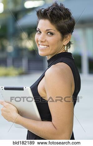 Stock Photo - Caucasian woman holding digital tablet outdoors. Fotosearch