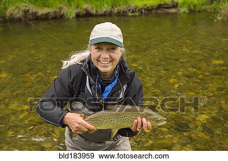 Caucasian woman holding fish in remote river View Large Photo Image Stock Photo - Caucasian woman holding fish in remote river. Fotosearch