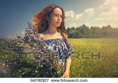 Caucasian woman holding flowers in rural field View Large Photo Image Stock Photo - Caucasian woman holding flowers in rural field. Fotosearch