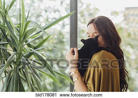 Stock Image - Caucasian woman holding kitten. Fotosearch