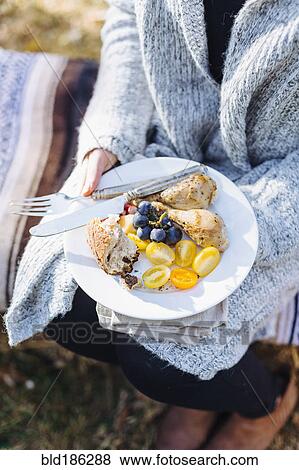 Stock Photo - Caucasian woman holding plate of food outdoors. Fotosearch