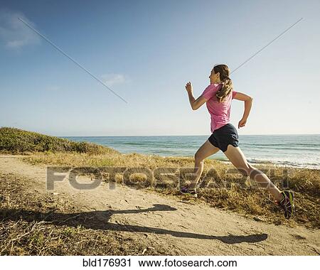 Stock Image - Caucasian woman jogging on beach. Fotosearch