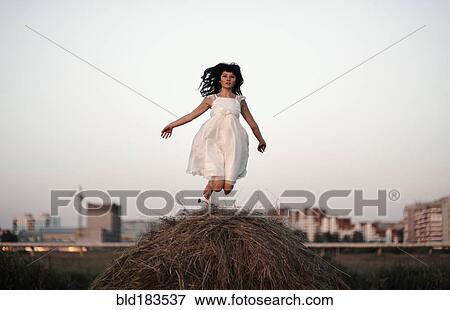Stock Photo - Caucasian woman jumping on haystack. Fotosearch