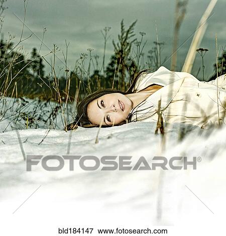 Stock Photo - Caucasian woman laying in snow. Fotosearch