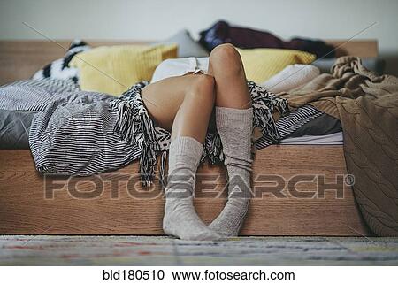 Stock Image - Caucasian woman laying on bed. Fotosearch